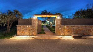 A gated entrance with a stone wall and a wooden archway, leading to a pathway.