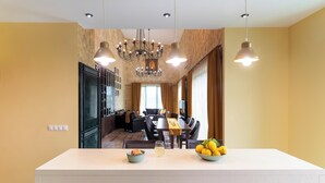 A modern kitchen with a central island, dining area, and a chandelier.