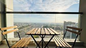 A balcony with a wooden table and two chairs, overlooking a cityscape with buildings and highways. - Upscale Studio Apartment Business Bay with Balcony and Free Parking by BelVilla (Dubai)
