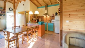 A wooden interior with a kitchen area, dining table, and chairs.