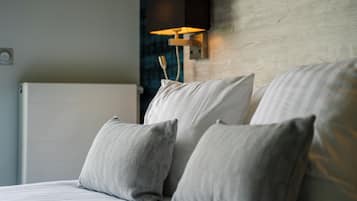 A neatly made bed with pillows and a wall-mounted lamp.