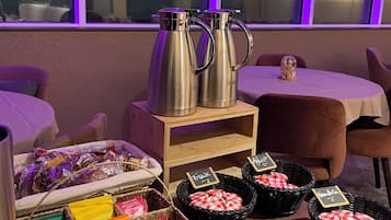 Morgenmadsbuffet med kaffekopper, kurve med bagværk og færdigpakkede varer.