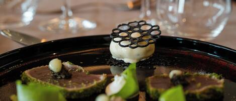 A dessert plate with a central piece of cake and surrounding garnishes.