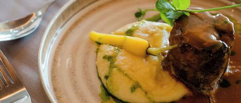 A plate with mashed potatoes, a piece of meat, and a garnish.
