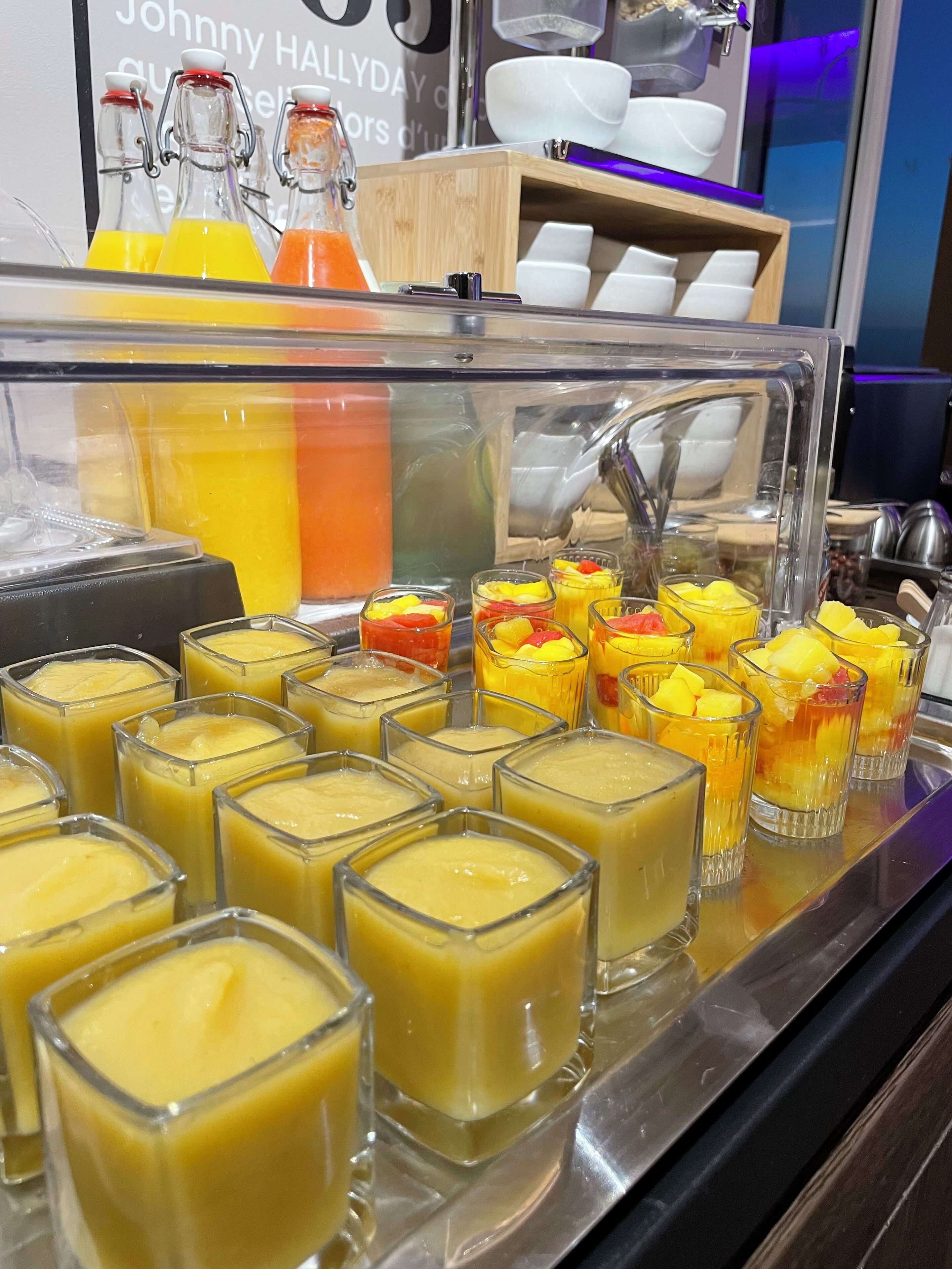 Un buffet con diversi cibi, tra cui coppette di frutta e un distributore di bevande.