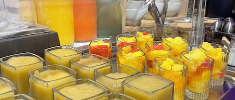 A buffet with various food items including fruit cups and a beverage dispenser.