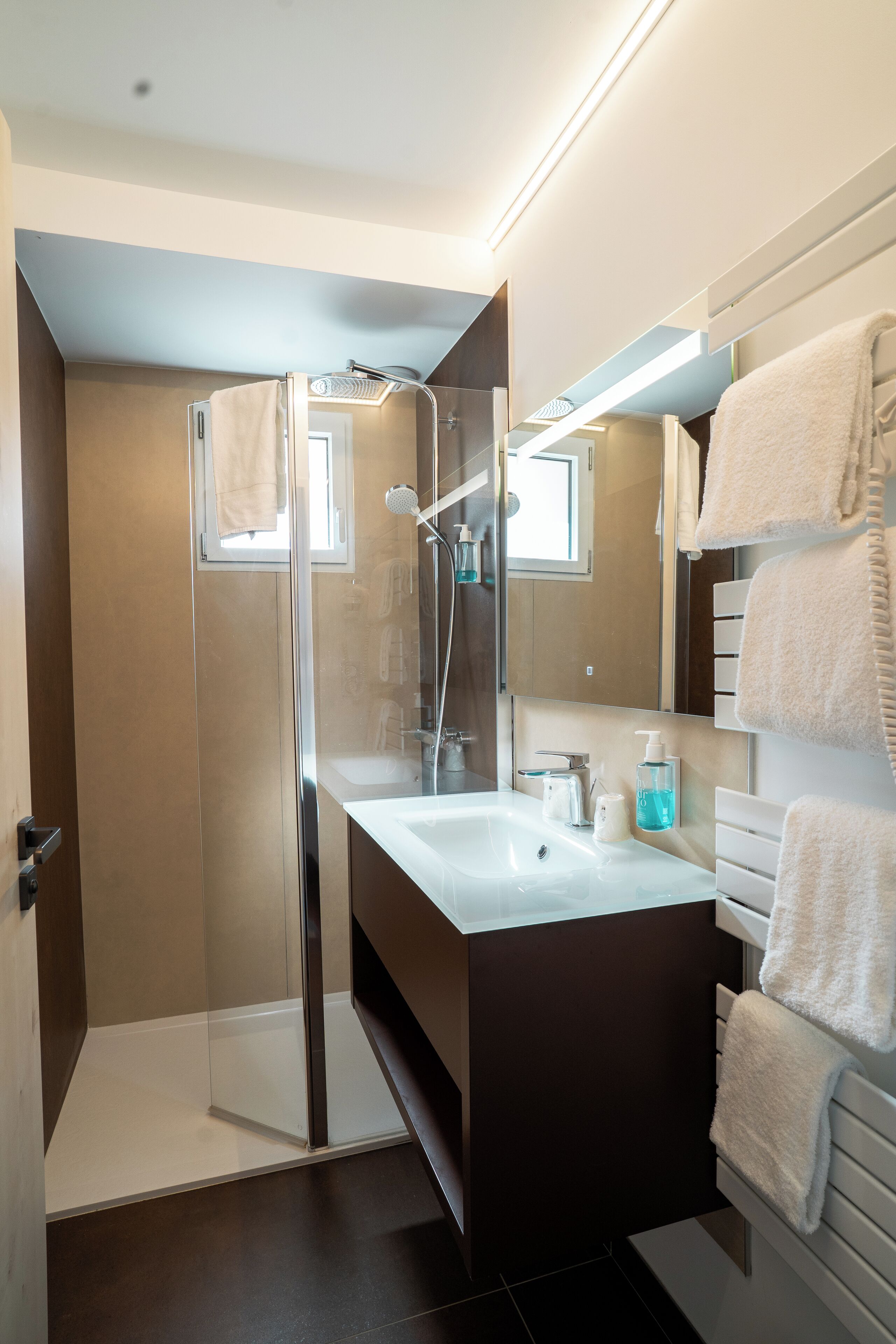 Un bagno moderno con doccia vetrata, lavandino bianco e uno specchio grande.
