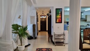 A hallway with a potted plant, a hanging light fixture, and a metal cart. - Gustavo Homes Mombasa (Mombasa)
