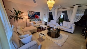 A modern living room with a sofa, coffee table, and a large plant. - Gustavo Homes Mombasa (Mombasa)