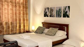 A hotel room with a bed, a desk, and a chair. There are four wall-mounted pictures of plants.