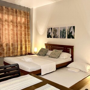 A hotel room with a bed, a desk, and a chair. There are four wall-mounted pictures of plants. - Jora Residences (Dagupan)