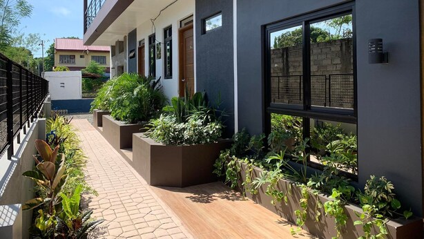 A modern building with a covered walkway, large windows, and outdoor planters.