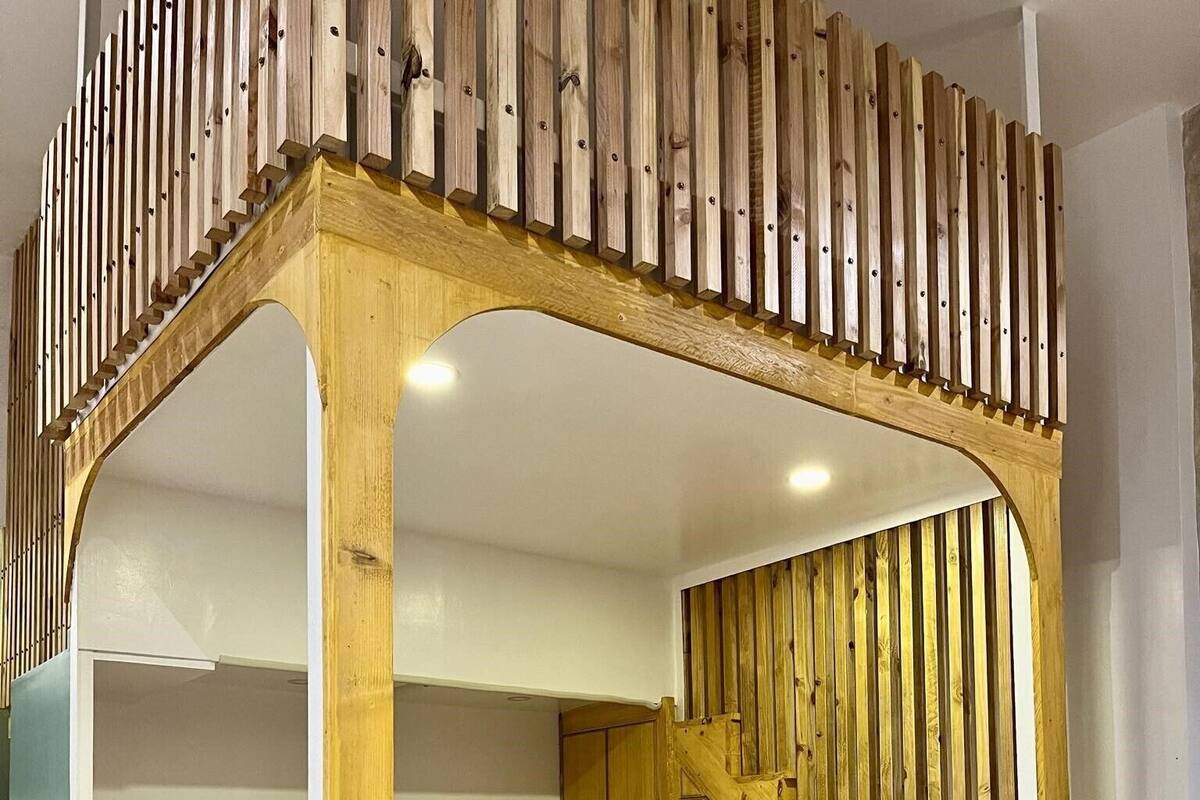 Un dormitorio con una cama a dosel de madera, una escalera y un armario.