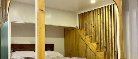 Ein Schlafzimmer mit einem hölzernen Baldachinbett, einer Treppe und einem Kleiderschrank.