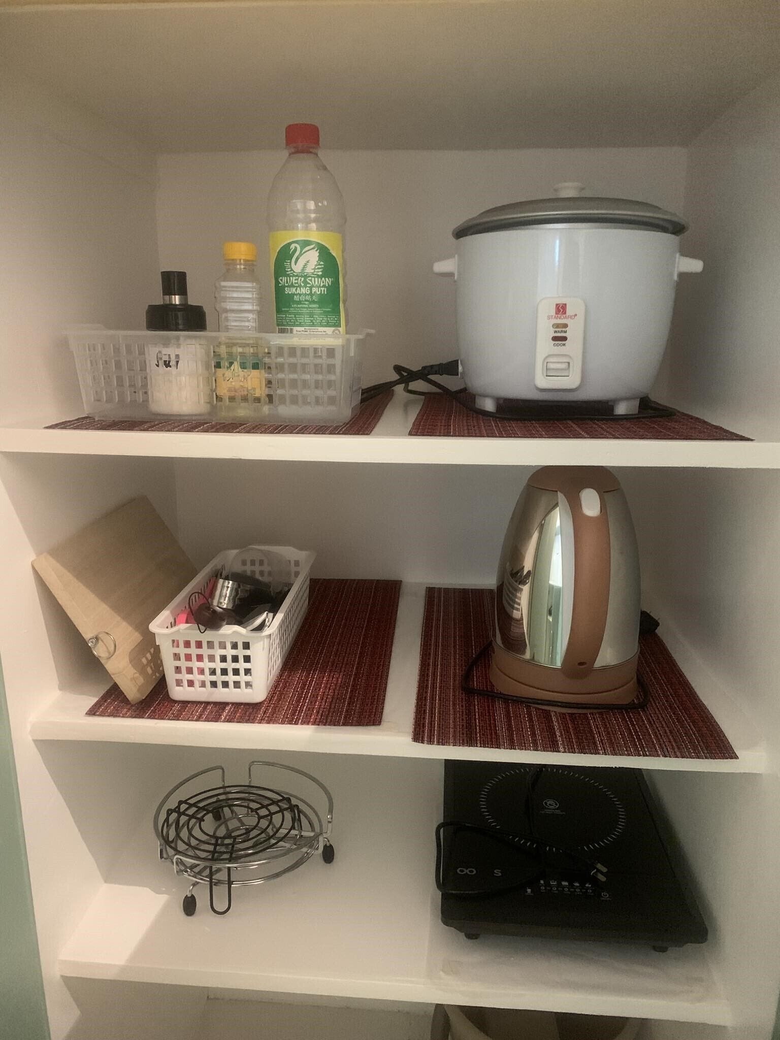 Uno scaffale da cucina con una pentola a cottura lenta, un bollitore e diversi oggetti per la cucina.
