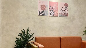A modern living room with a beige textured wall, a brown leather sofa, a wooden coffee table, and a potted plant.