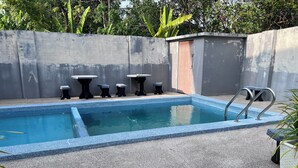 A rectangular pool with a blue edge, surrounded by a concrete deck. There are four small tables and a bench along the poolside. - OYO 90967 Homestay Chalet Warisan Siti  (Langkawi)