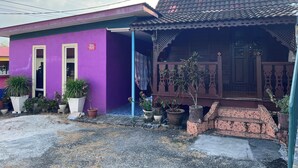 A two-story house with a purple exterior and a brown roof. There are potted plants and a staircase leading to the upper floor. - OYO 90967 Homestay Chalet Warisan Siti  (Langkawi)