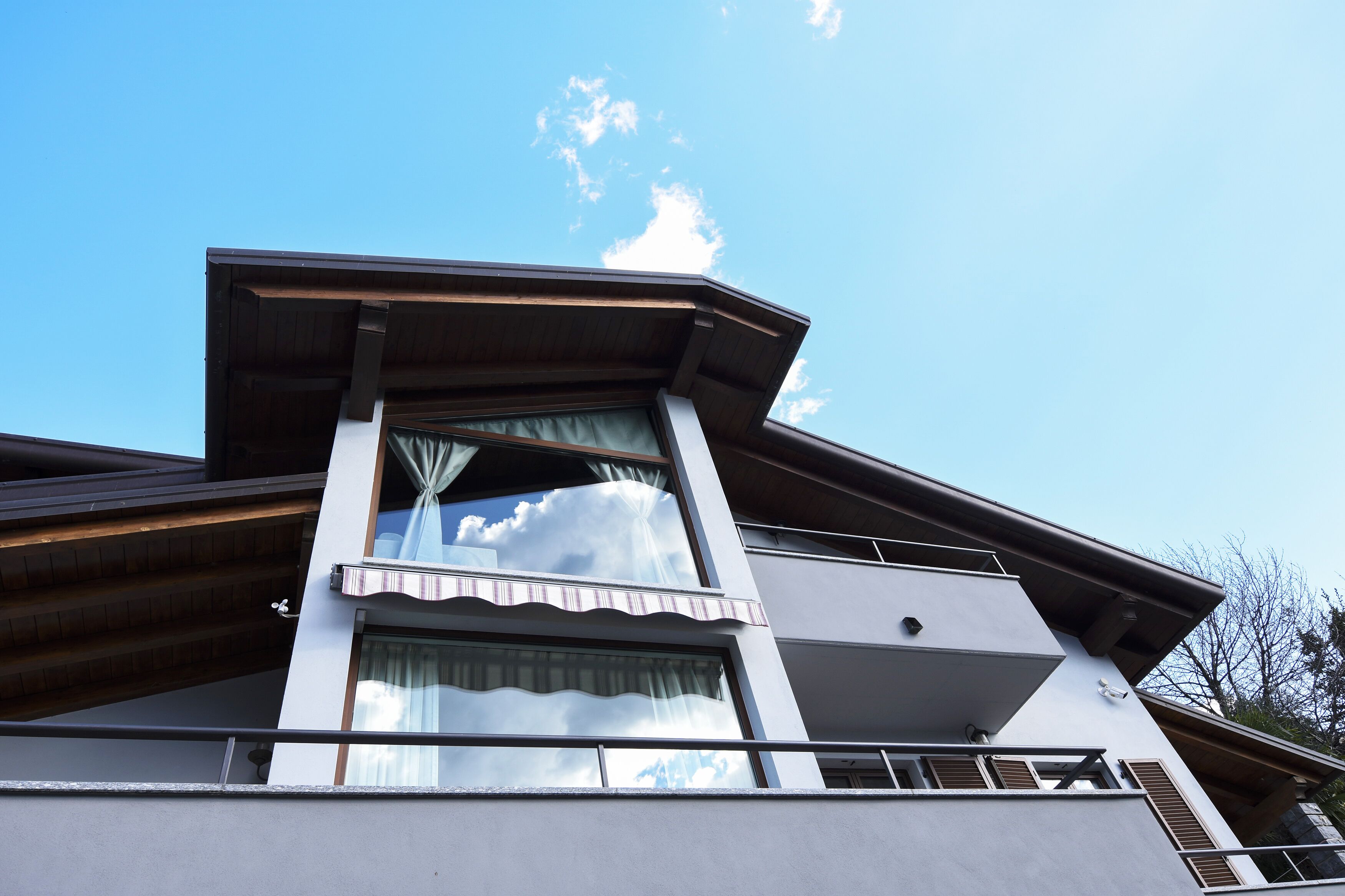 A modern building with a prominent balcony, large windows, and a clear sky.