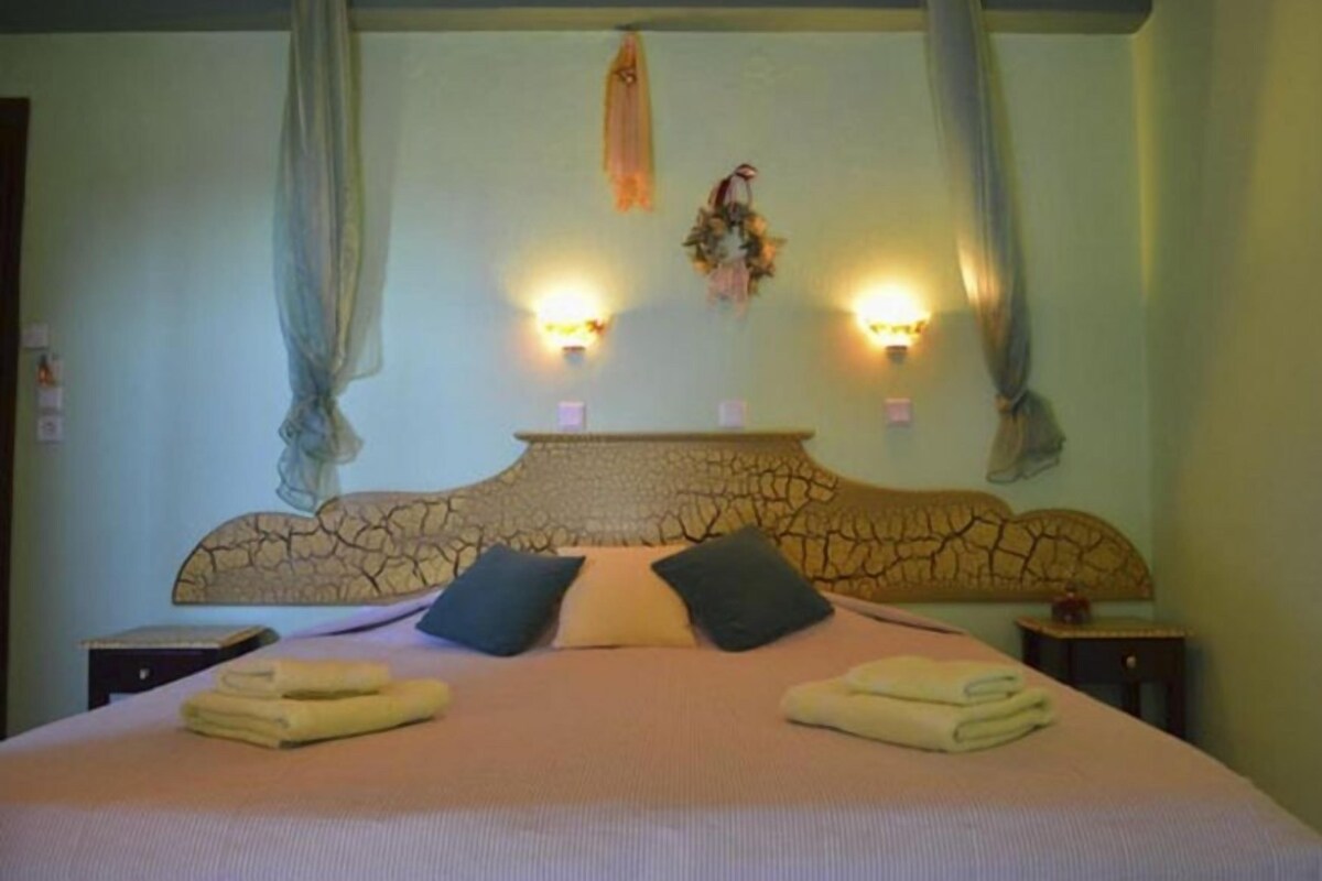 A bedroom with a large bed, two bedside tables, and a headboard with a cracked pattern.