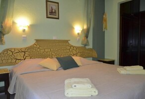 Una habitación de hotel con una cama, dos lámparas de noche, una mesita de noche y una puerta.