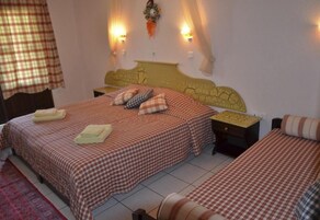 Una habitación con dos camas, cada una con ropa de cama a cuadros, cabeceros, mesitas de noche y luces fijadas a la pared.