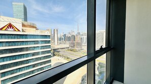 A cityscape view from a high-rise building with modern architecture, including a distinctive red and yellow logo on a building to the left. - Spacious Studio Apartment Burj View with Balcony Free Parking by Belvilla (Dubai)