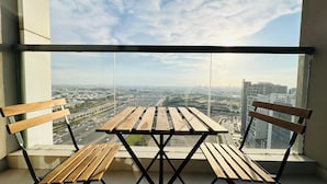 A balcony with a wooden table and two chairs, overlooking a cityscape with buildings and highways. - Spacious Studio Apartment Burj View with Balcony Free Parking by Belvilla (Dubai)