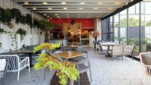 An indoor dining area with tables and chairs, a red wall, and large windows. - INNO CONCEPT HOTEL (Antalya)