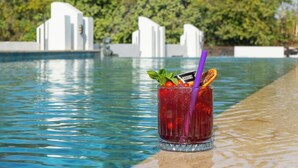 A poolside setting with a glass of red drink garnished with mint, a straw, and a slice of orange. - INNO CONCEPT HOTEL (Antalya)