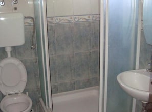 Une salle de bain comprenant des toilettes, un lavabo et un espace douche.