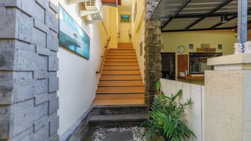 Un escalier étroit mène à un palier du deuxième étage, avec un petit espace extérieur en contrebas.