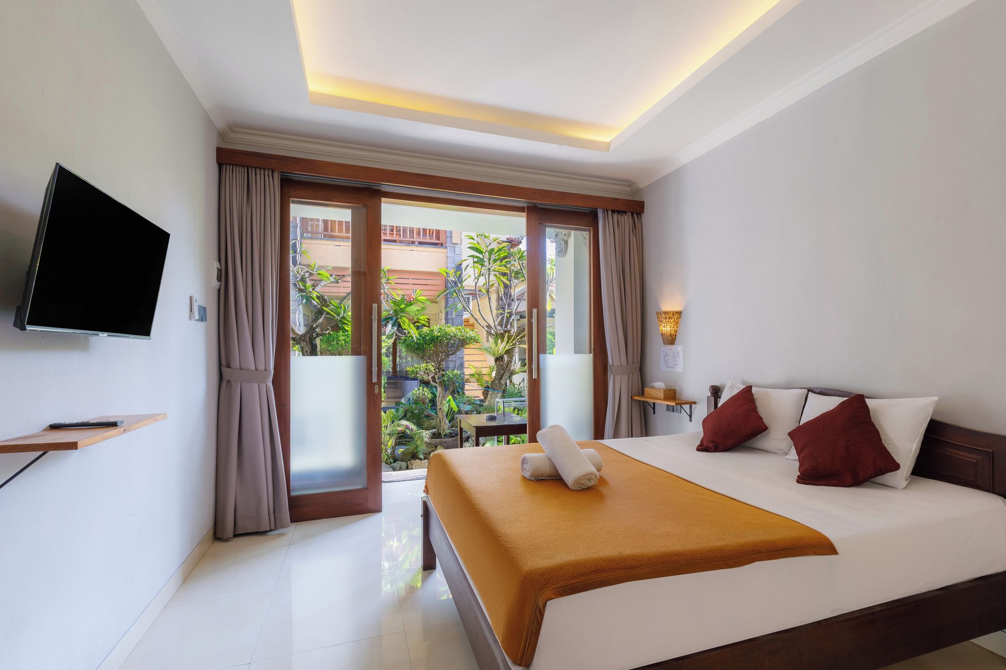 A hotel room with a bed, a TV, a desk, and a view of the outside.