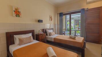 A hotel room with two beds, a nightstand, a small table, and a window with curtains.