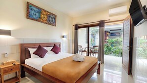 A well-lit bedroom with a large bed, a nightstand, a TV, and a sliding glass door leading to an outdoor area. - Donahome (Denpasar)