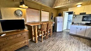 A compact kitchen with wooden furniture, a refrigerator, and a television. - Star Gazer  Hideaway (Bisbee)