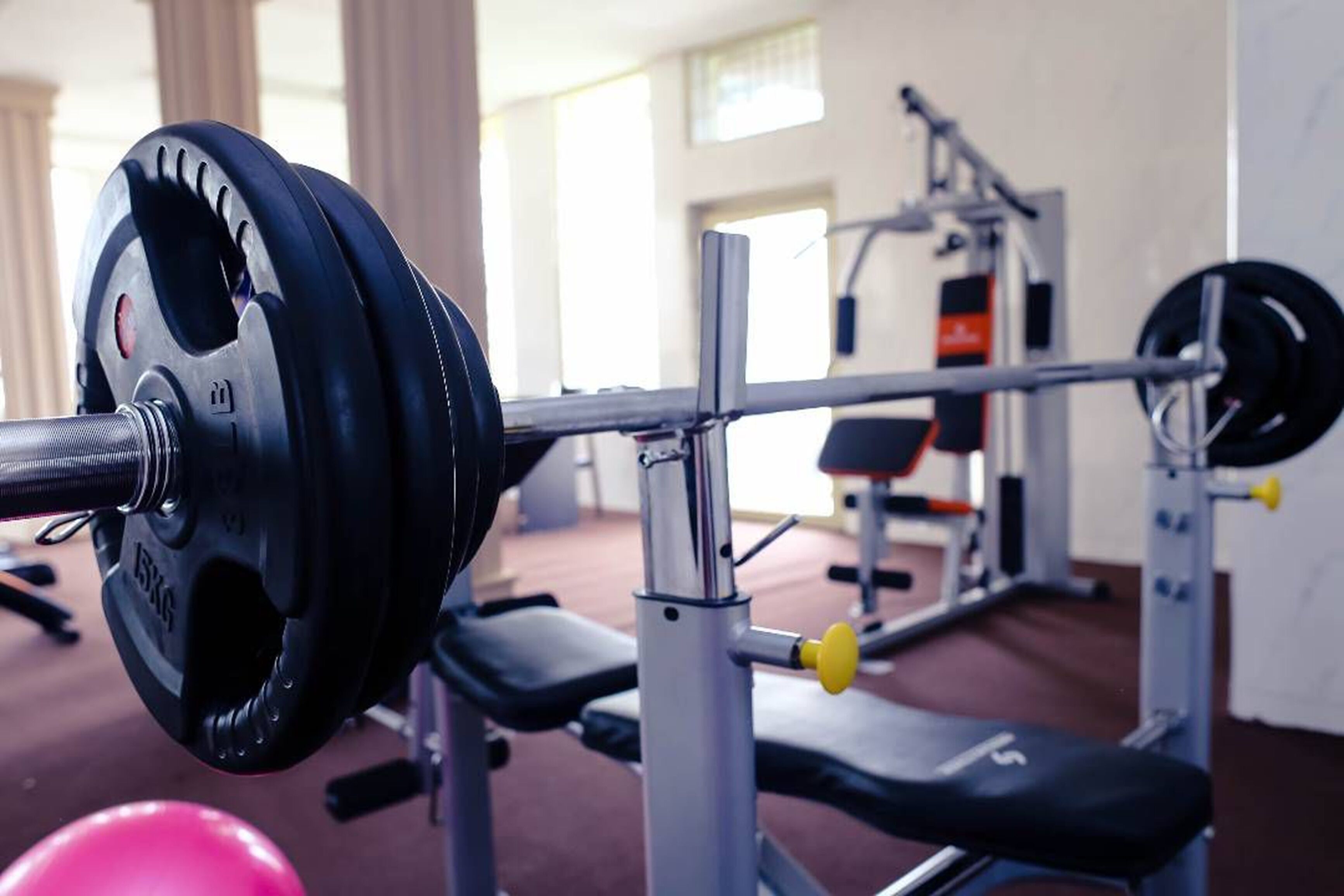 Un banc de musculation avec une barre chargée de disques de poids dans une salle de sport.