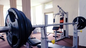 A weightlifting bench with a barbell loaded with weight plates in a gym. - Mo-House Hotel and Event Center (Abuja)