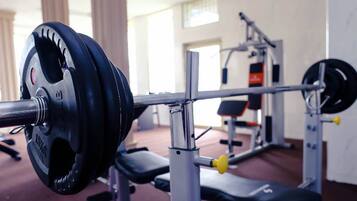 Un banc de musculation avec une barre chargée de disques de poids dans une salle de sport.