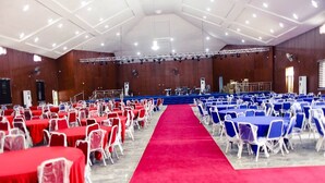 A large hall with rows of tables and chairs, a red carpet, and a stage with musical instruments. - Mo-House Hotel and Event Center (Abuja)