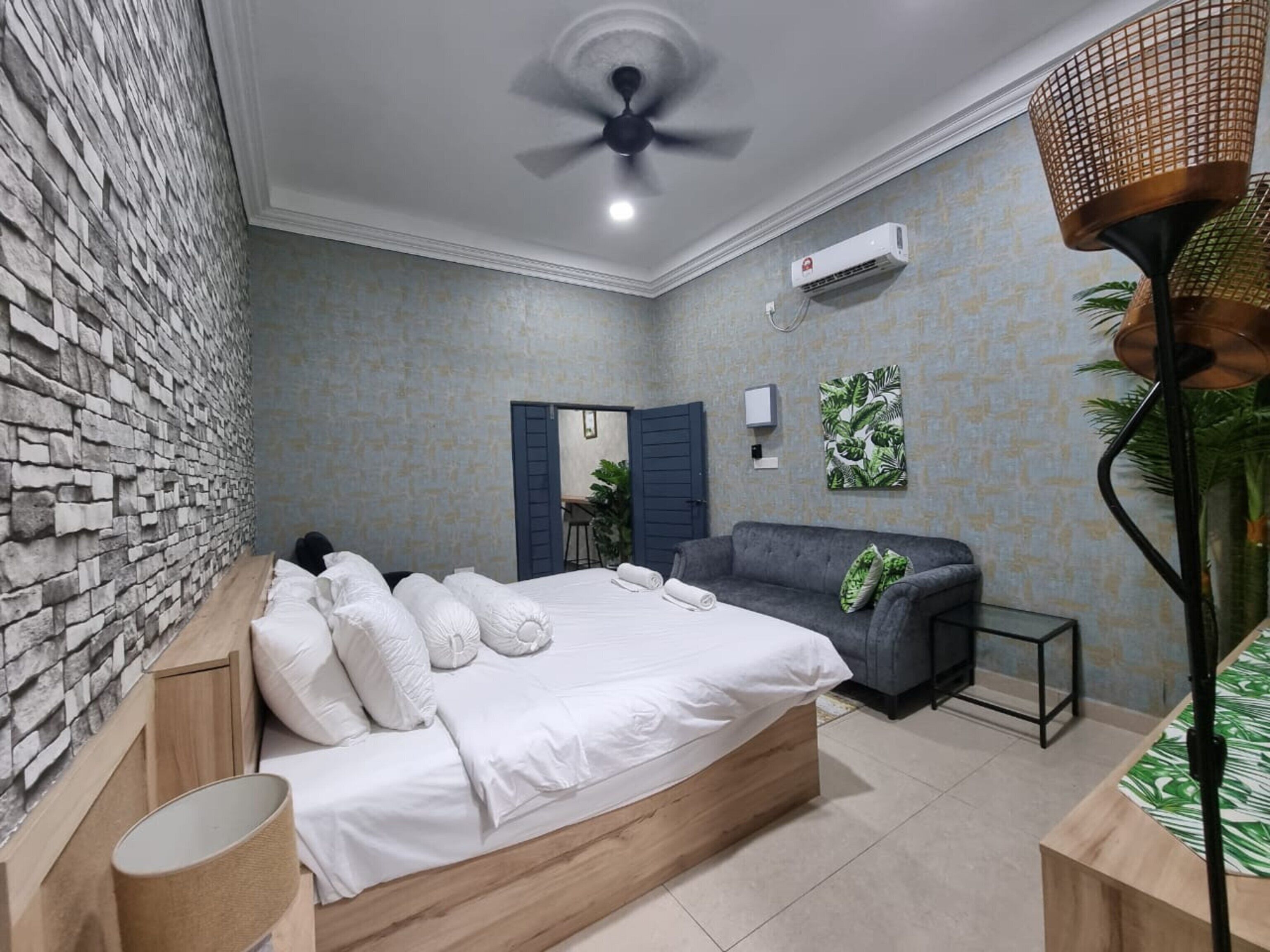 Une chambre à coucher comprenant un lit, un canapé, un bureau, une lampe et un ventilateur de plafond.