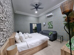A bedroom with a bed, a sofa, a desk, a lamp, and a ceiling fan.