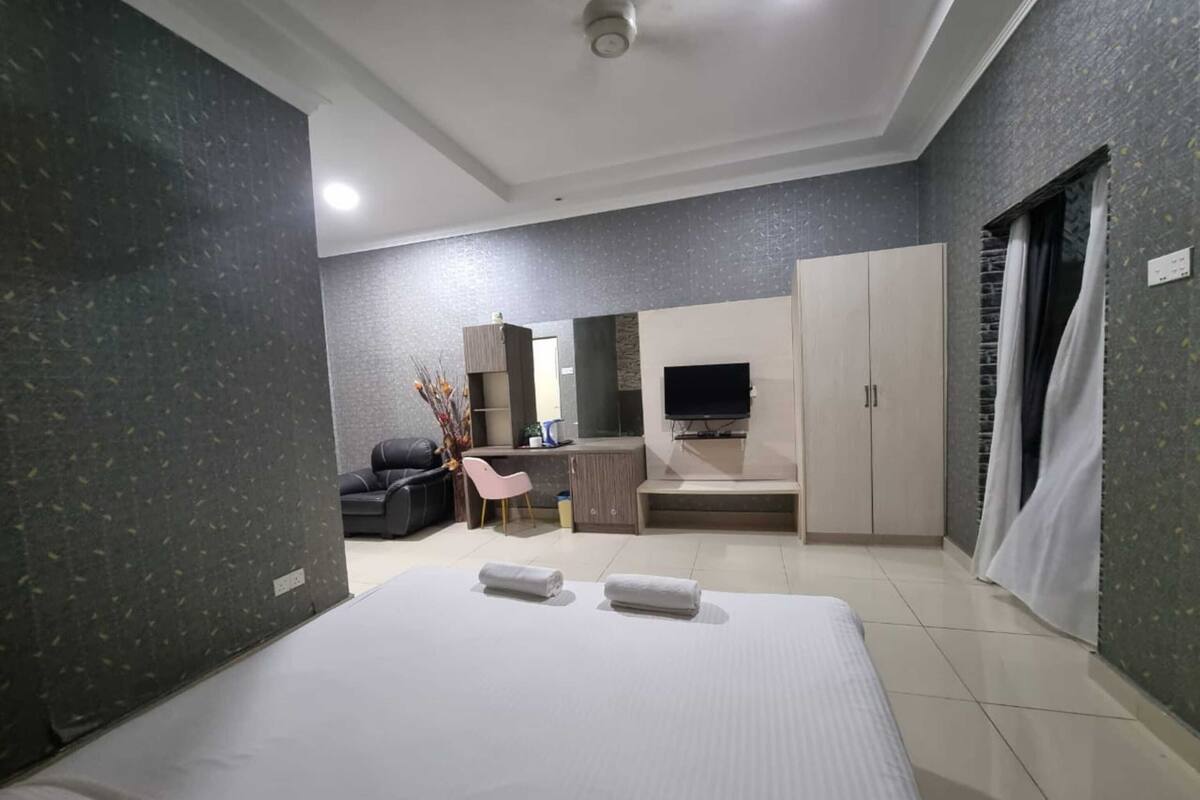 Una habitación de hotel moderna con una cama grande, un escritorio, un sofá y un televisor.