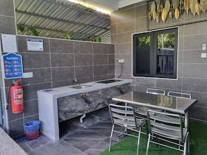 A modern bathroom with a marble sink, a window, and a fire extinguisher.