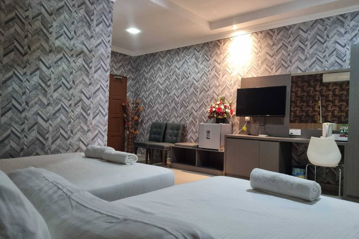 Una habitación de hotel con dos camas, un escritorio, un televisor y un minibar.