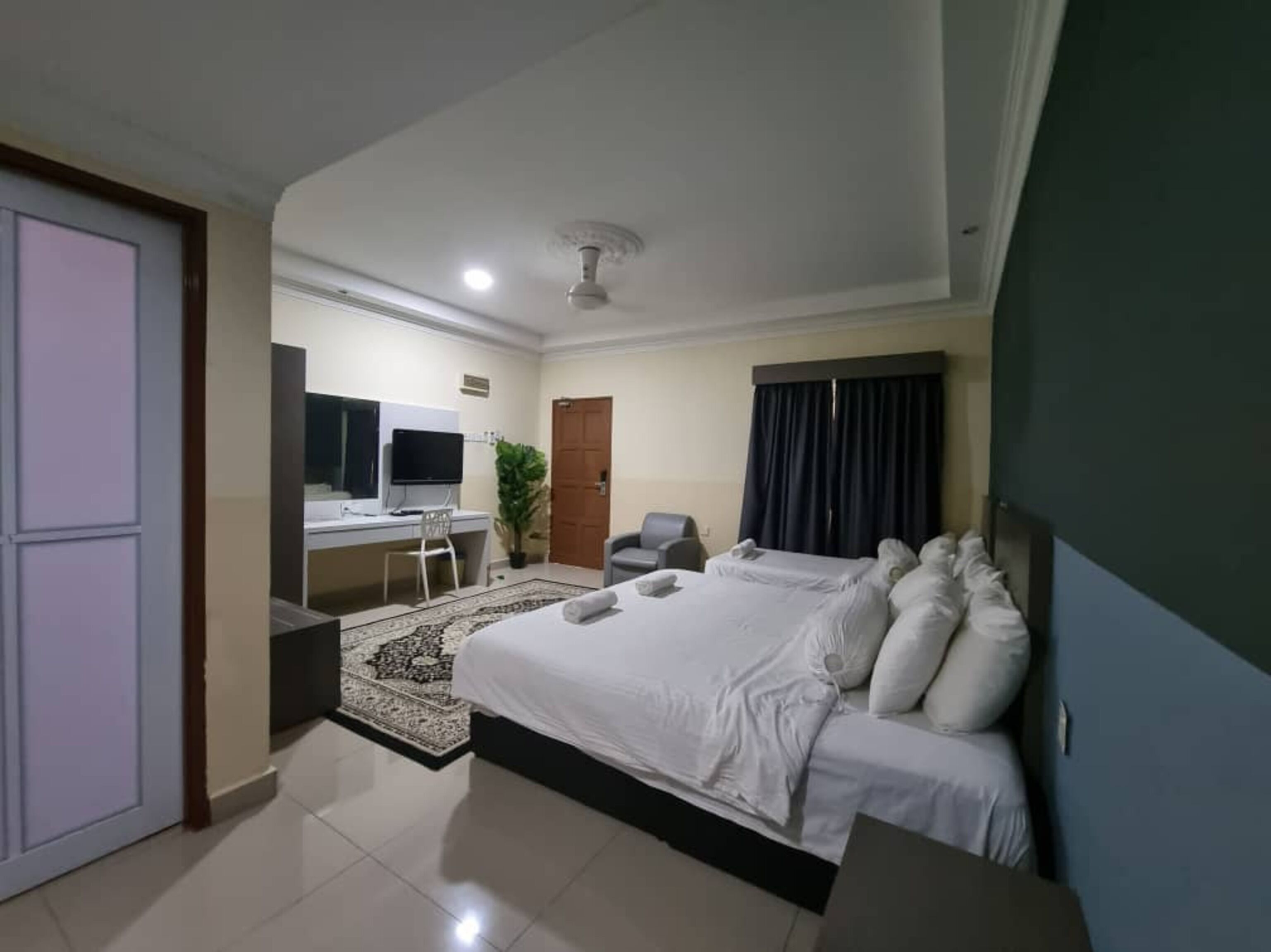 A hotel room with a bed, desk, chair, and a television.