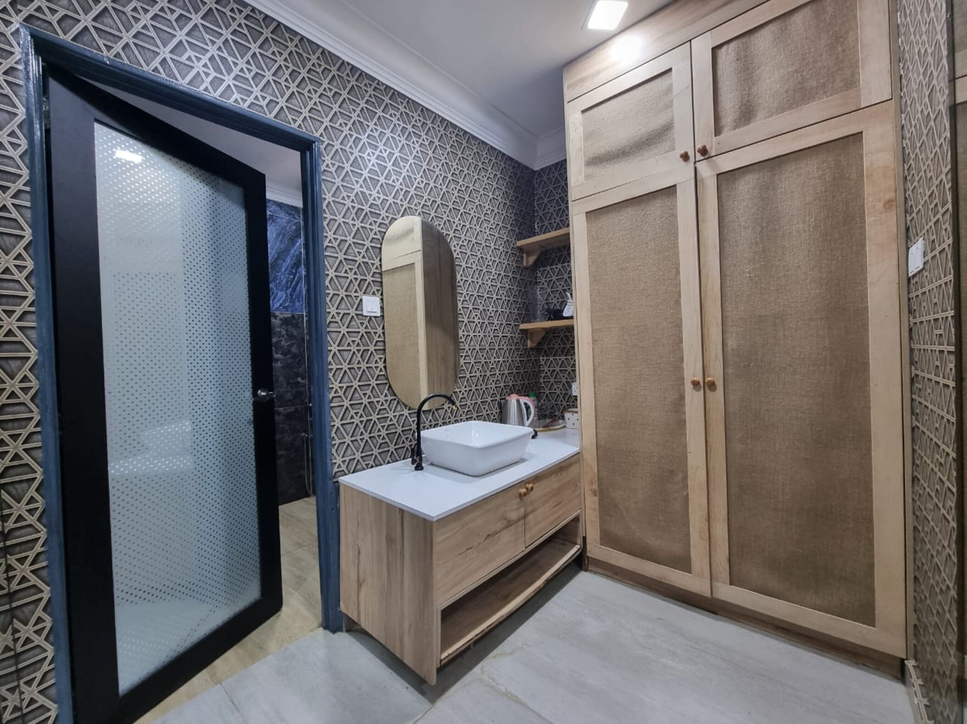 A bathroom with a modern design, featuring a freestanding sink, a mirror, and a wardrobe with multiple doors.