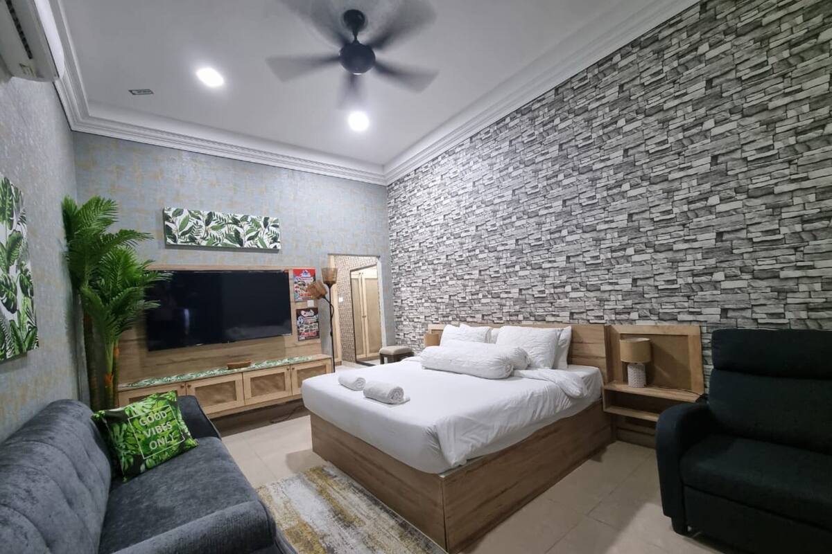 Un dormitorio moderno con pared de piedra, cama, televisor y sofá.