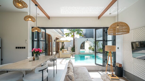 A modern kitchen with a dining area, a pool, and a large window. - Villa Honey (Canggu)
