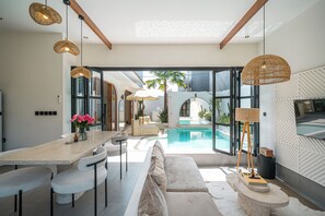 Una cocina moderna con comedor, piscina y un ventanal grande.